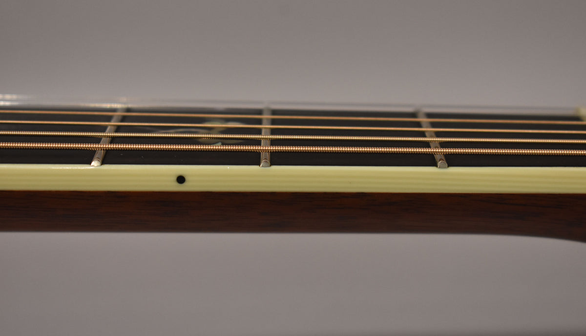 A close-up of the guitar's dark fretboard and light binding, showing copper strings, frets, and a single black side dot.