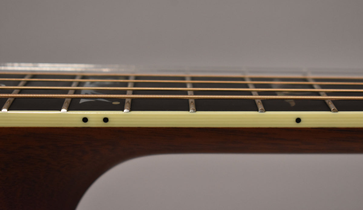 Close-up of the guitar's dark fretboard and light-colored binding, showing the frets, strings, and side dot markers.