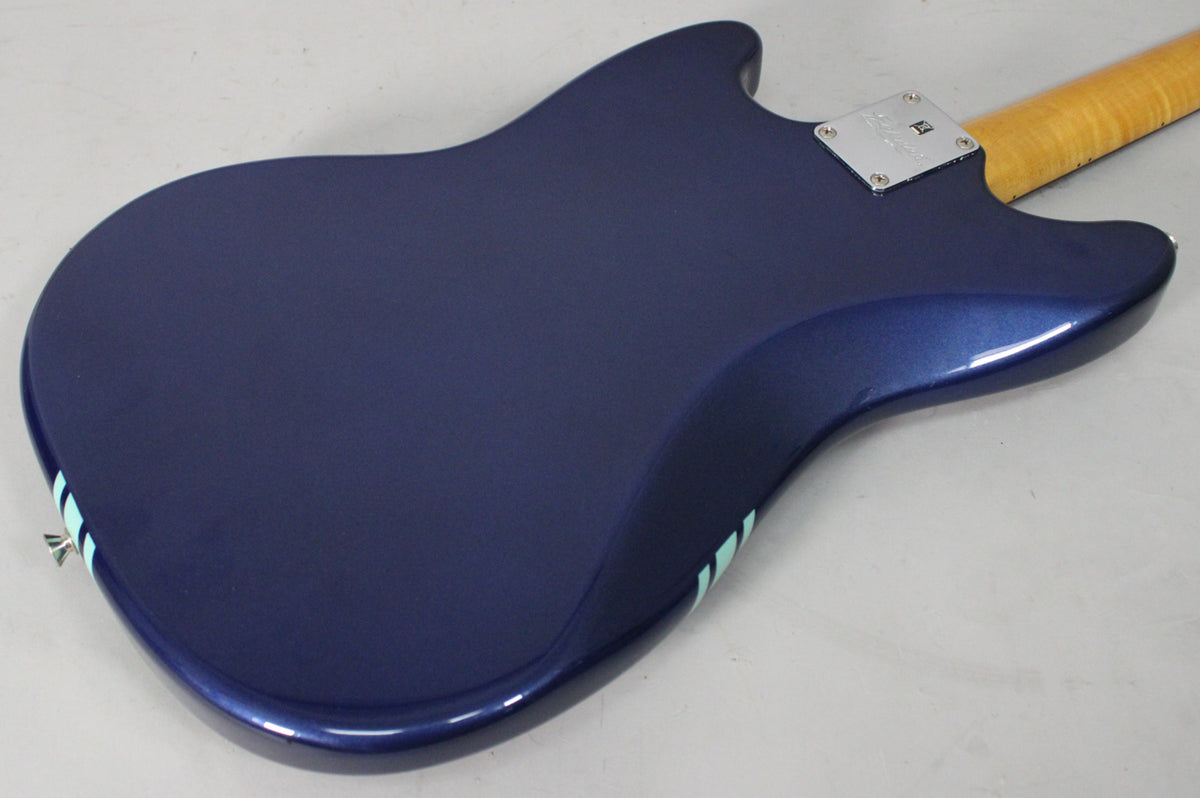 The back of a metallic blue guitar with two light blue racing stripes on the lower bout, and a maple neck.