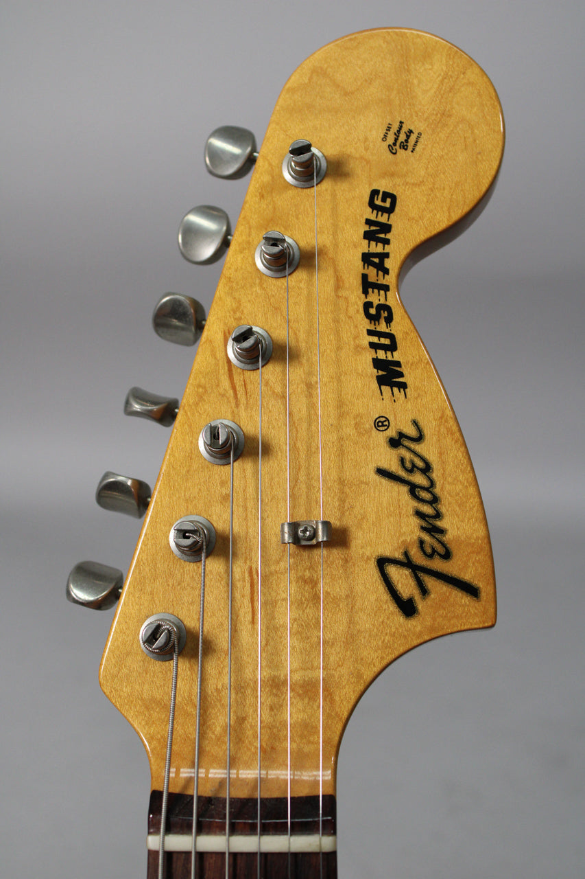 Close-up of the guitar's amber-tinted headstock, showing six brushed chrome tuners, a string tree, and light finish wear.