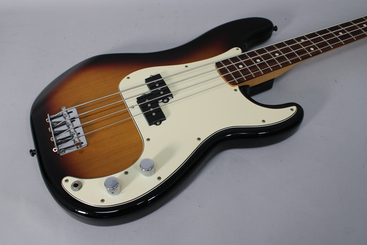 Sunburst bass, angled from above, showing the body, white pickguard, split pickup, chrome bridge, and two control knobs.