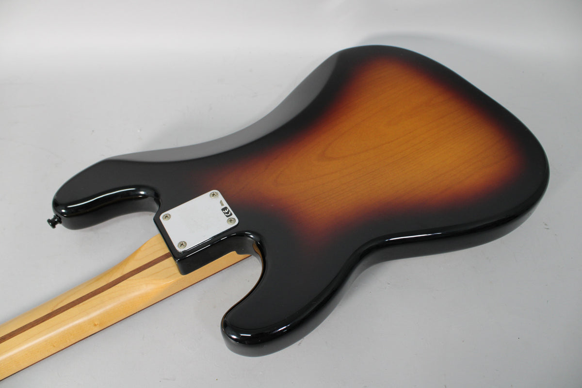 The bass's sunburst body, with a glossy finish, is seen from the back, angled to show the neck joint and strap button.