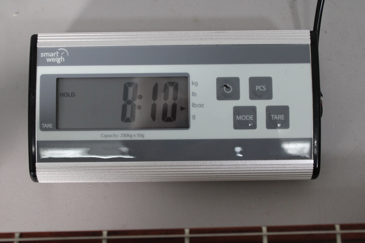 A Smart Weigh digital scale displays "8:10" in large digits, with "lb:oz" illuminated, showing the bass's weight.