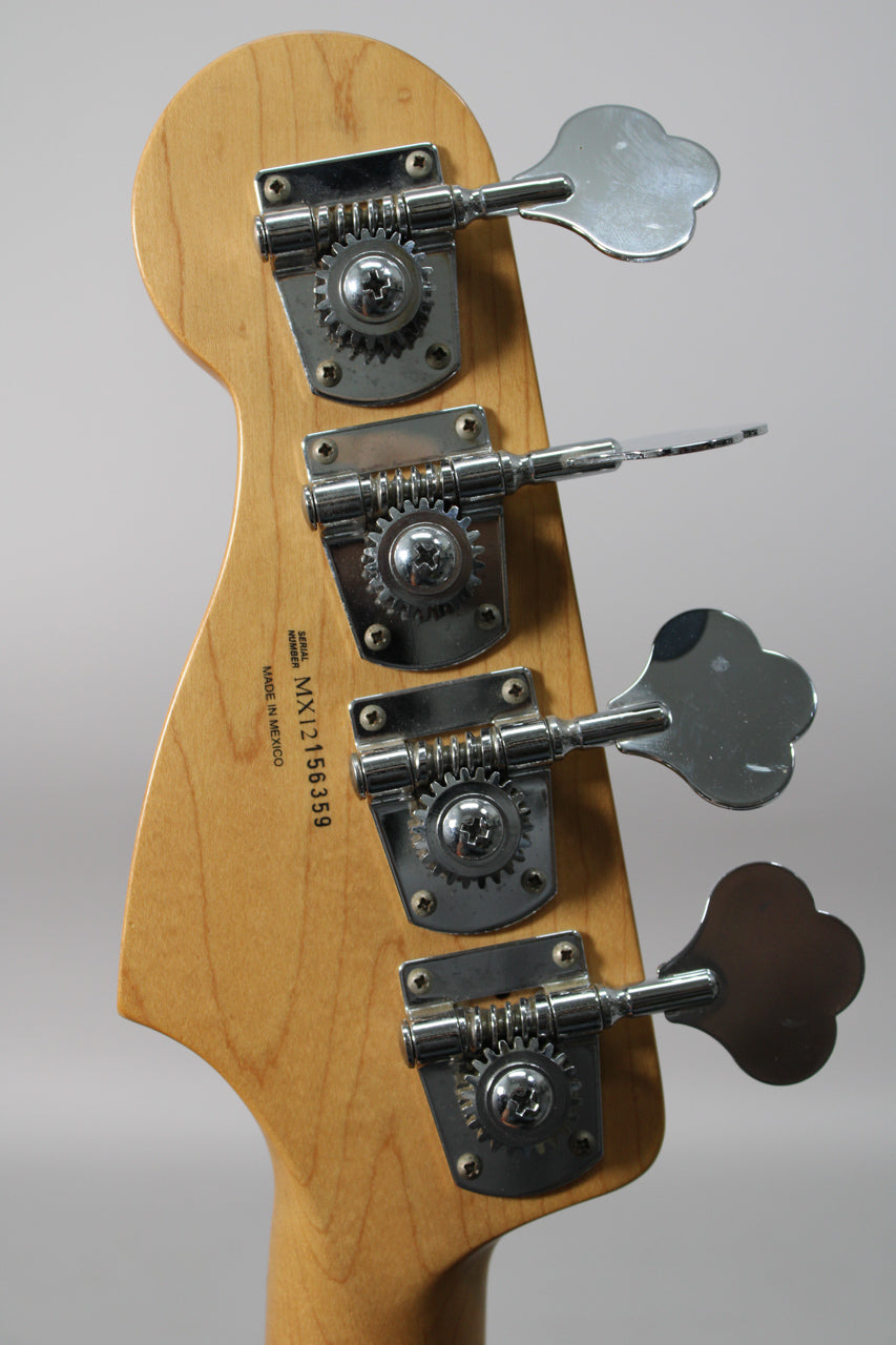The back of a light wood bass headstock with four chrome clover-leaf tuners, showing some light wear and scratches.