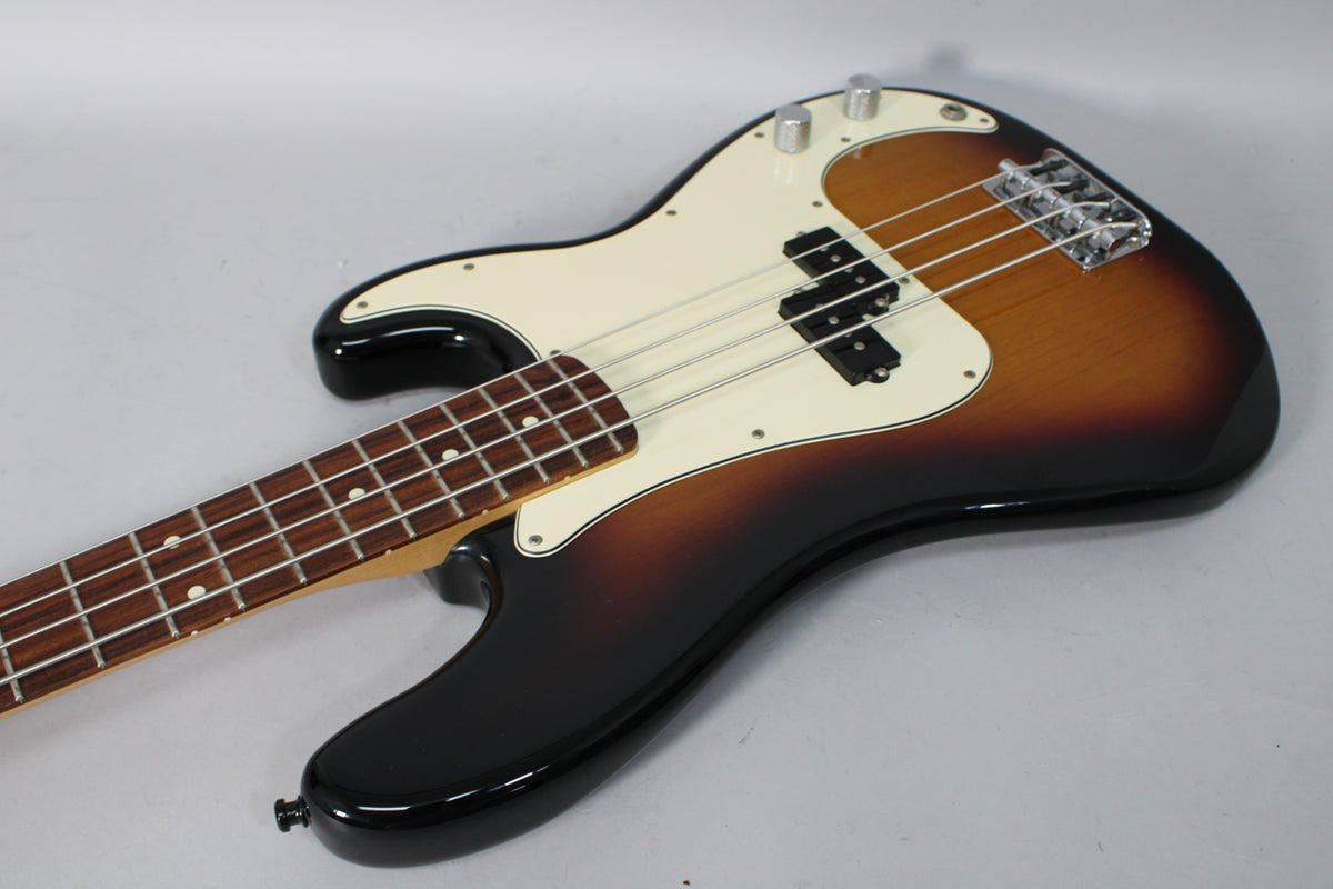 Sunburst P-Bass, angled from the lower bout, showing the body, cream pickguard, split pickup, chrome bridge, and two control knobs.