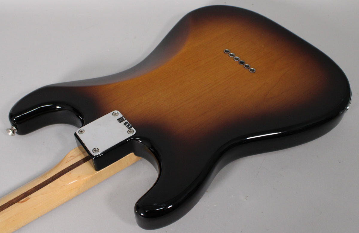 The guitar's glossy sunburst back shows a chrome neck plate, six string-through-body ferrules, and light wear on the lower bout.