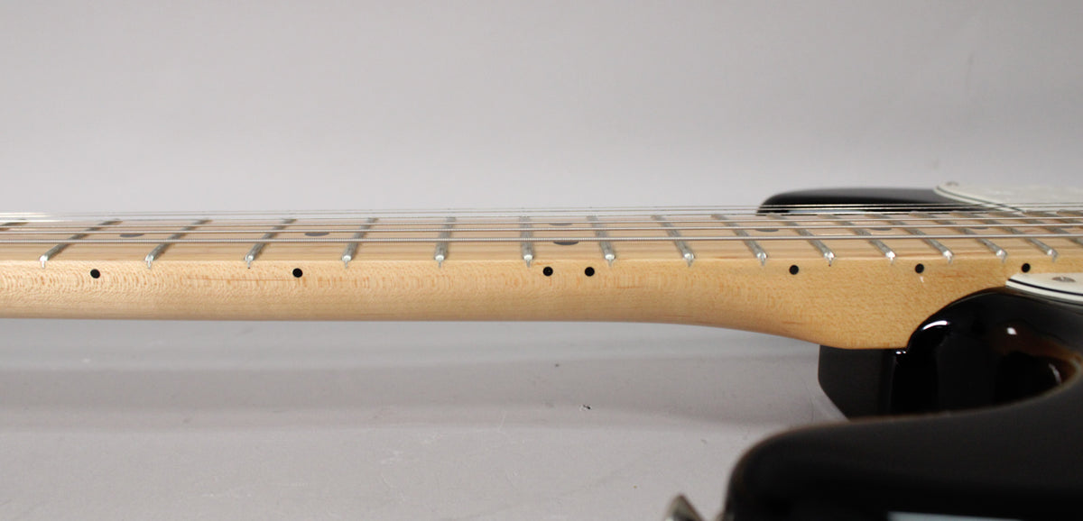 The guitar's maple neck and fretboard are shown in profile, with black dot inlays and a sunburst body visible at the bottom right.