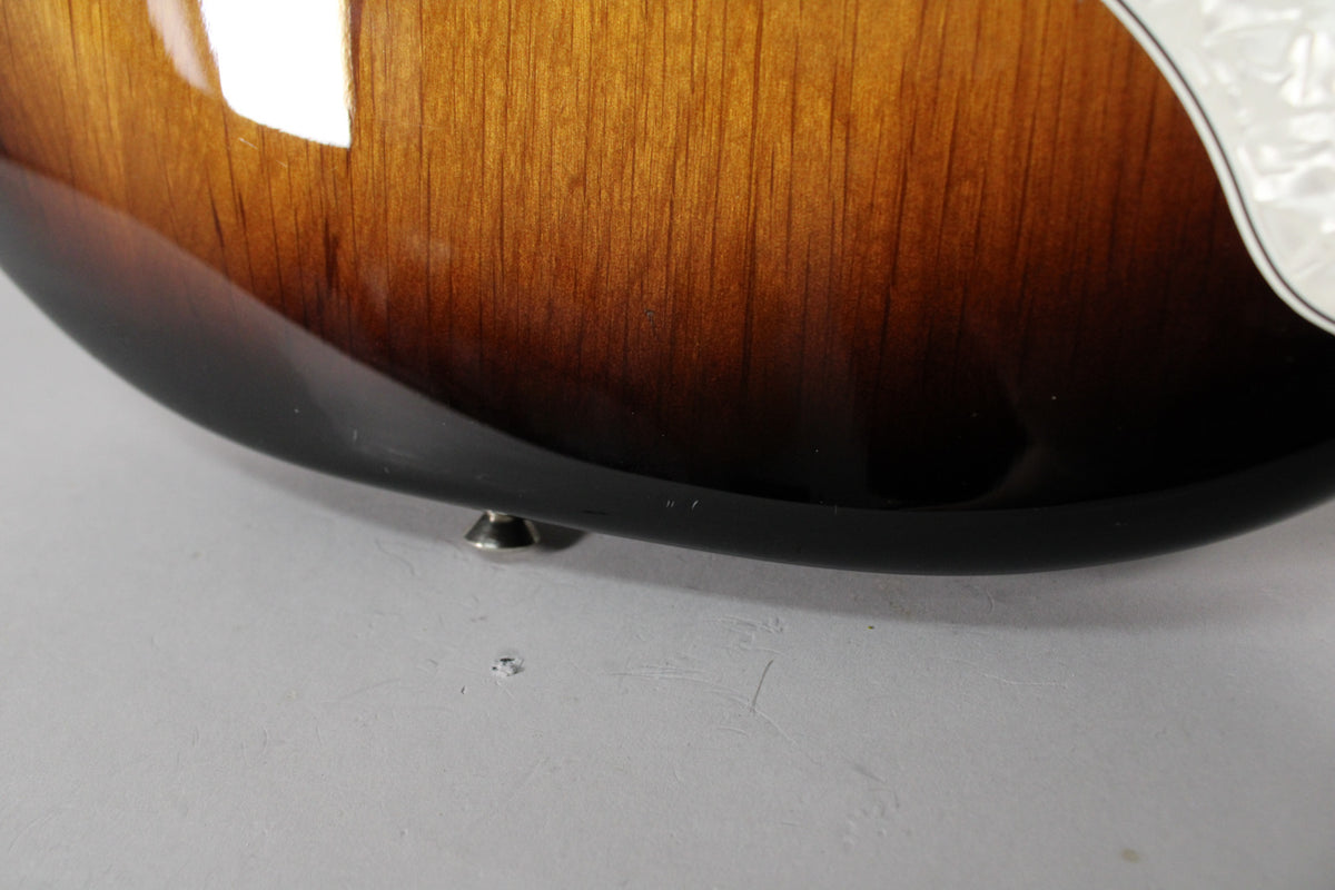 Close-up of the guitar's lower bout, showing the glossy 2-color sunburst finish with minor scuffs and a strap button.