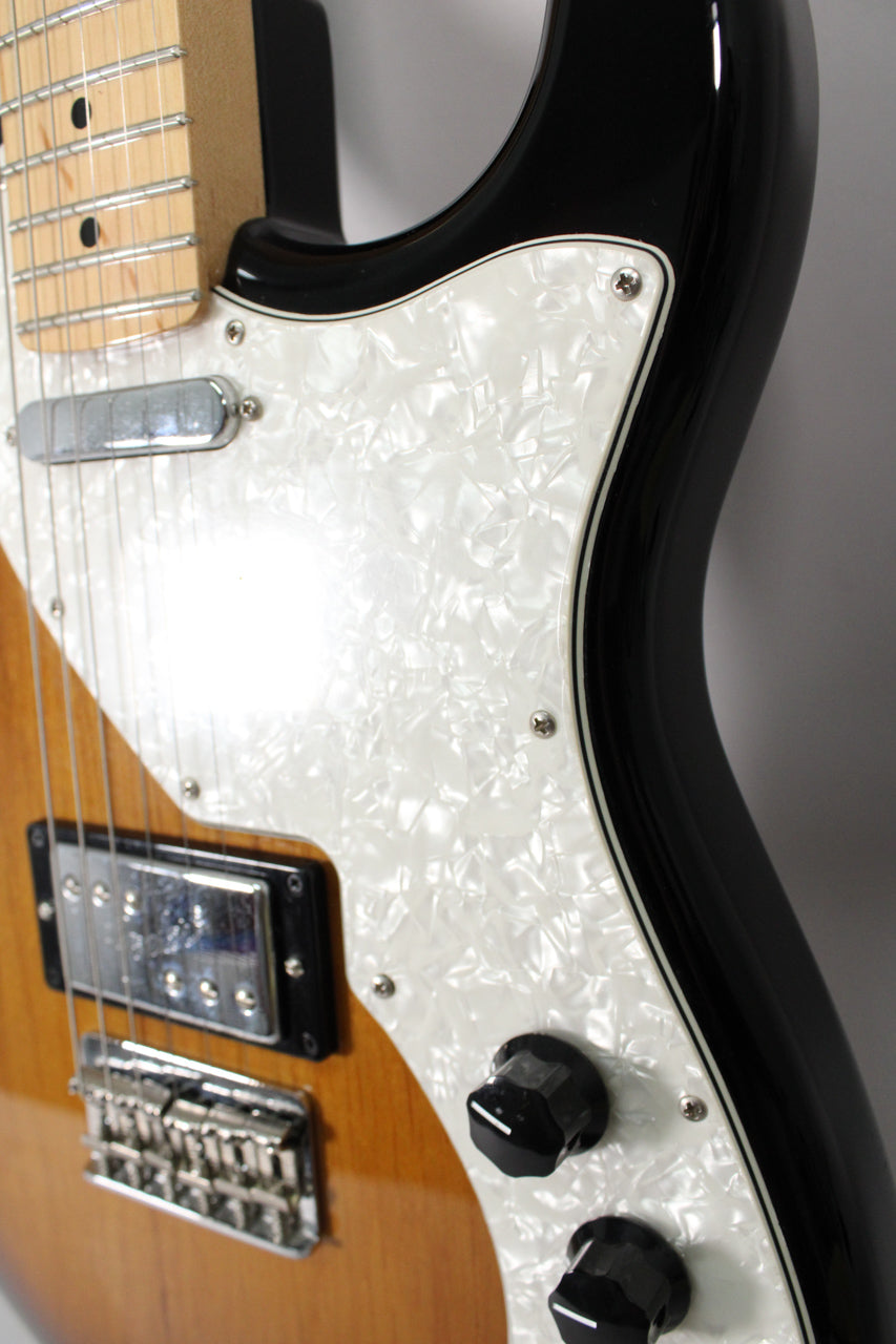 Close-up of the guitar's lower body, showing the pearloid pickguard, two black control knobs, humbucker, and bridge.