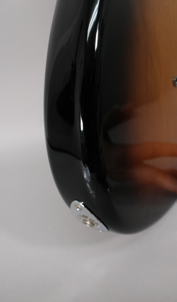 Close-up of the guitar's lower bout, showing the sunburst finish, chrome output jack, and a noticeable chip in the black finish.