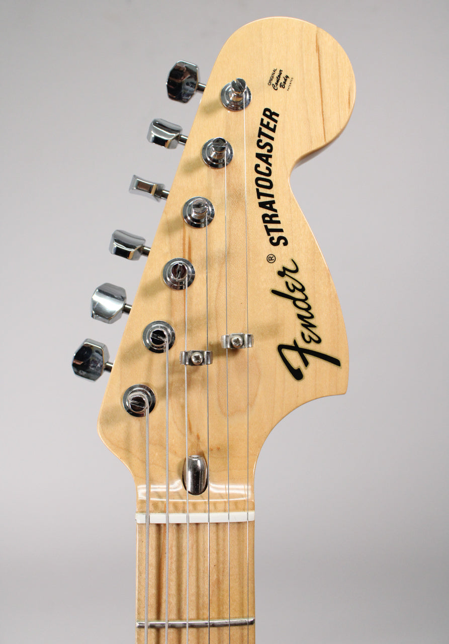 Close-up of the light maple headstock with six chrome tuners, two string trees, and a white nut over a maple fretboard.