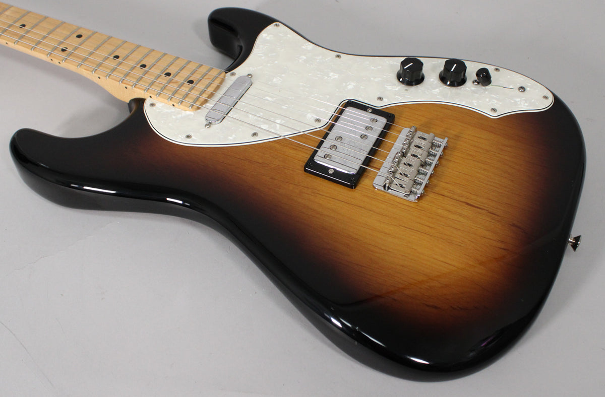 The sunburst guitar body is angled from the neck, showing a pearloid pickguard, a humbucker, and a single-coil pickup.