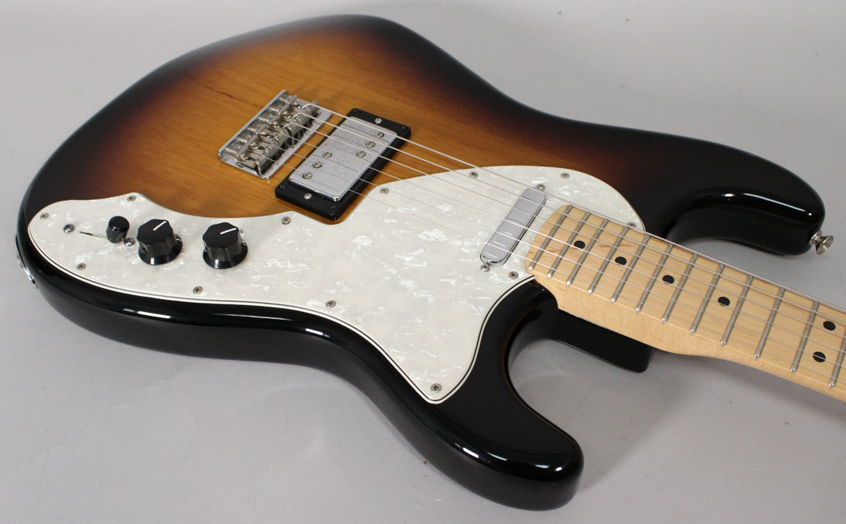 Sunburst guitar body, angled from above, showing a pearloid pickguard, two black control knobs, and a humbucker pickup.