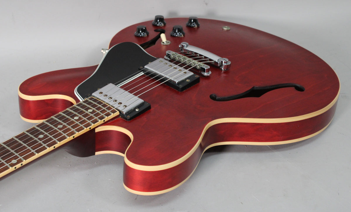 Cherry red satin finish ES-335 body with f-holes, black pickguard, two humbuckers, and four black control knobs.