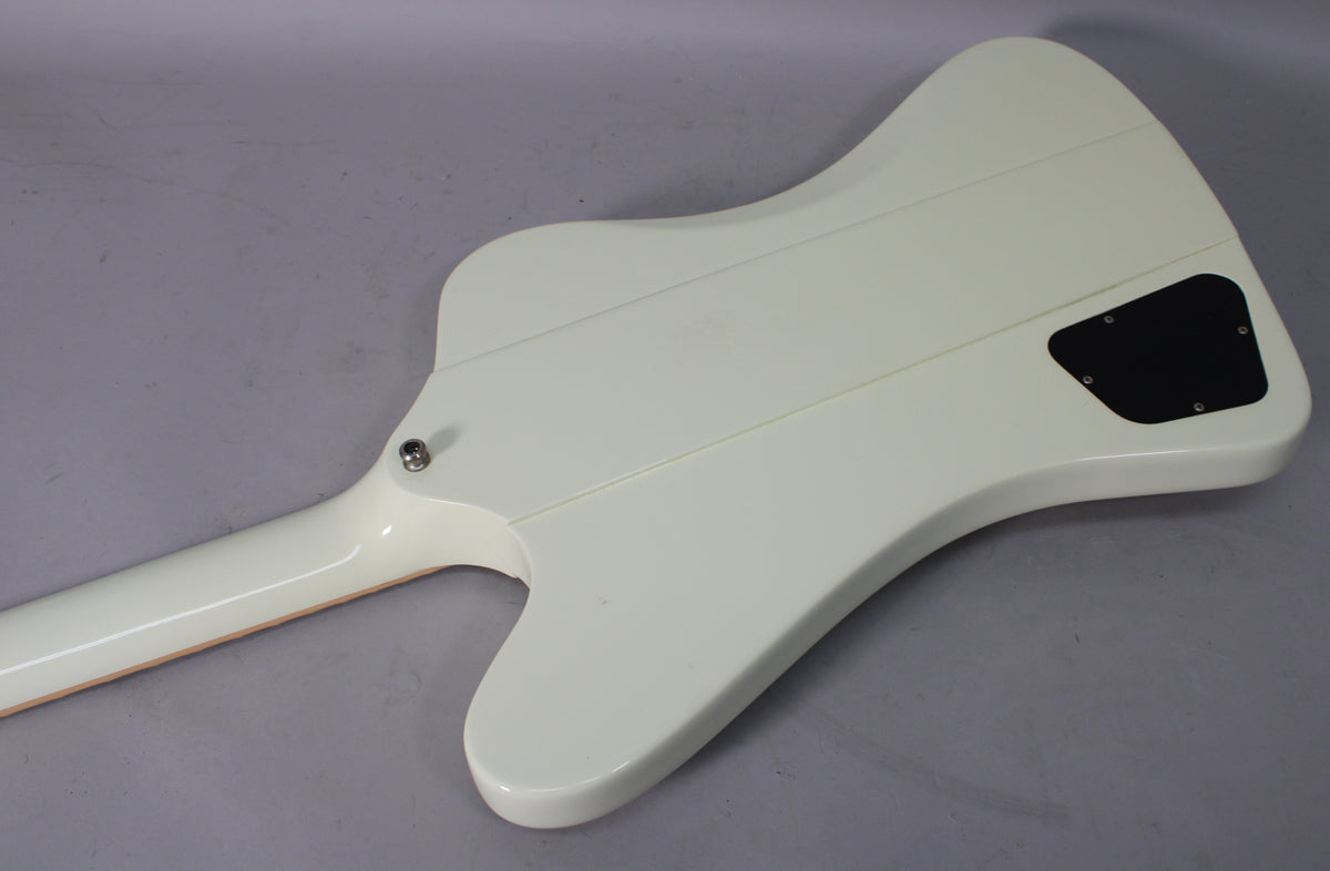 The back of the classic white guitar shows a black control cavity cover, a neck-through design, and a strap button near the neck joint.