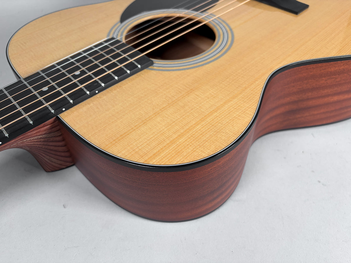Close-up of the guitar's lower bout and soundboard, showing the natural wood grain, dark pickguard, and multi-ring rosette.