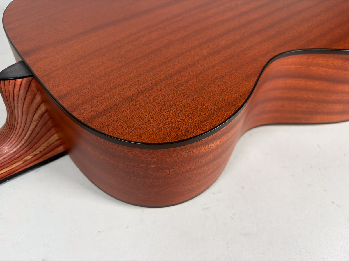 Close-up of the lower bout and cutaway of the natural finish acoustic guitar, showing the wood grain and black binding.