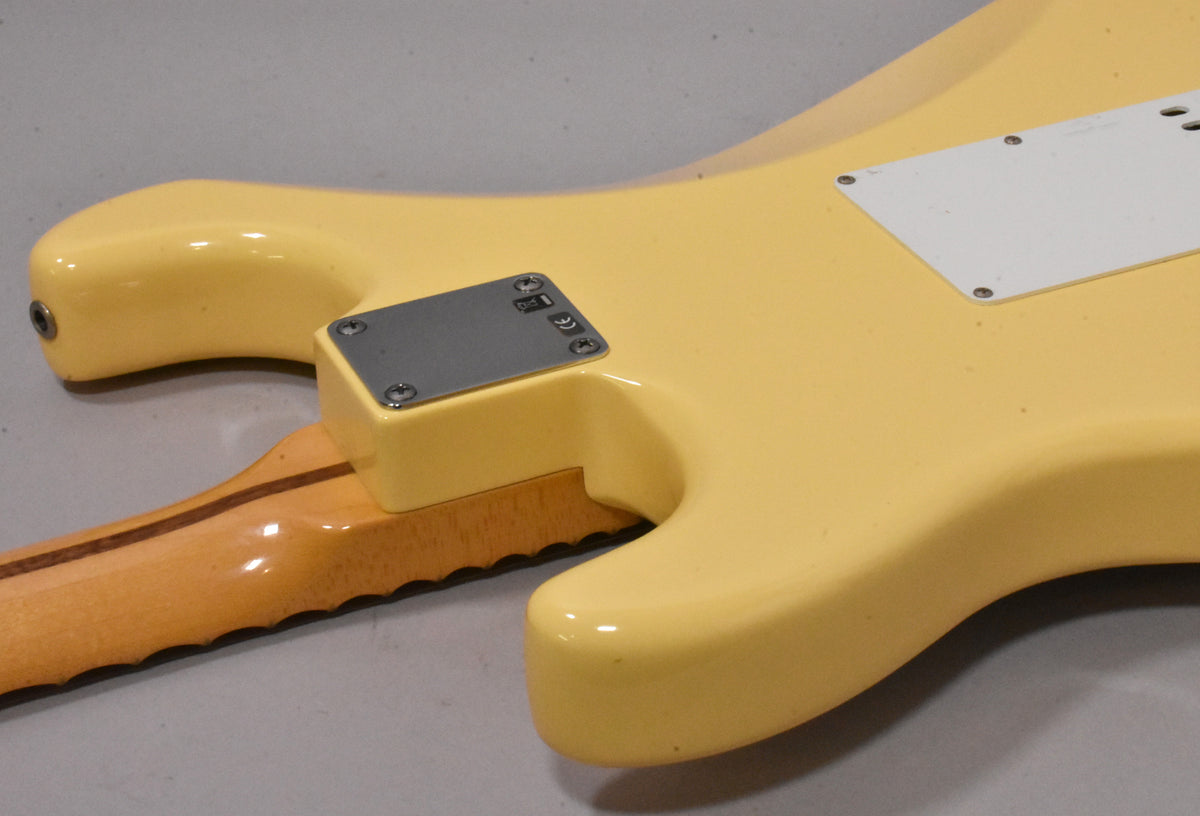 Close-up of the vintage white guitar's lower back, showing the neck plate, output jack, and a white tremolo cavity cover.