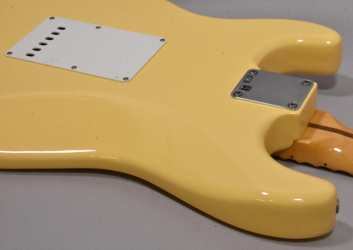 The back of a vintage white Stratocaster body, showing the tremolo spring cover, neck plate, and some minor finish wear.