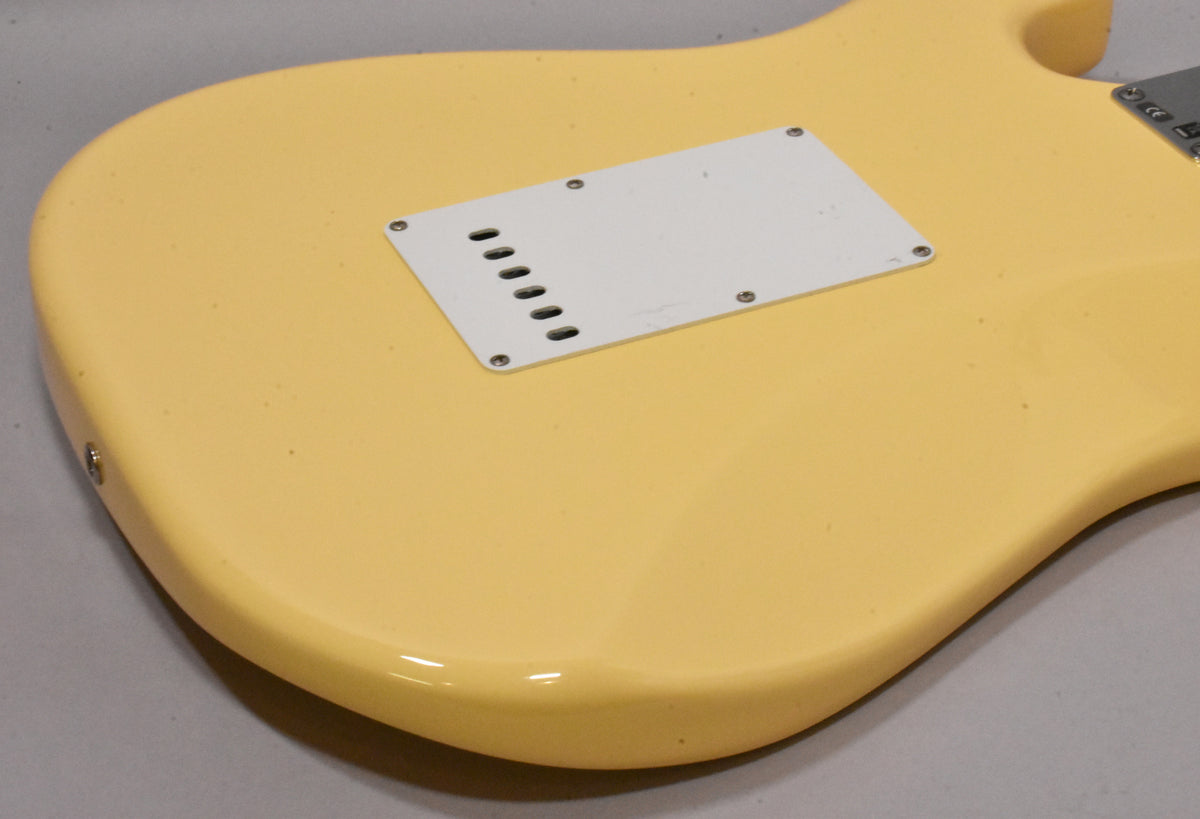 The vintage white guitar's lower back shows a white tremolo cover with six slots, secured by six screws, with minor scuffs.