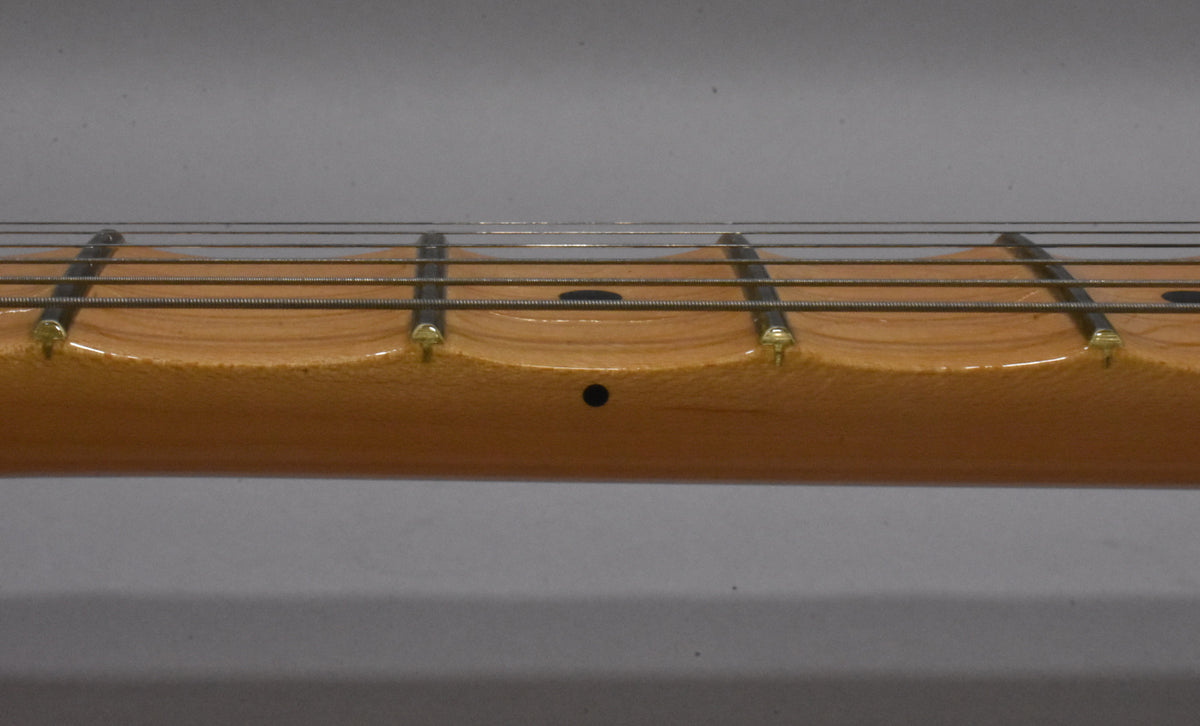 Close-up of the scalloped maple fretboard with dark fret markers and light wear on the frets and wood.