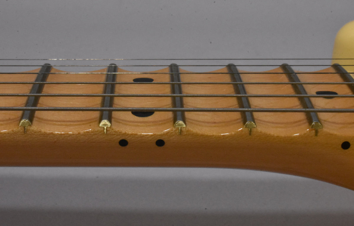 Close-up of the scalloped maple fretboard with dark dot inlays and gold-colored frets, showing wear along the lower edge.
