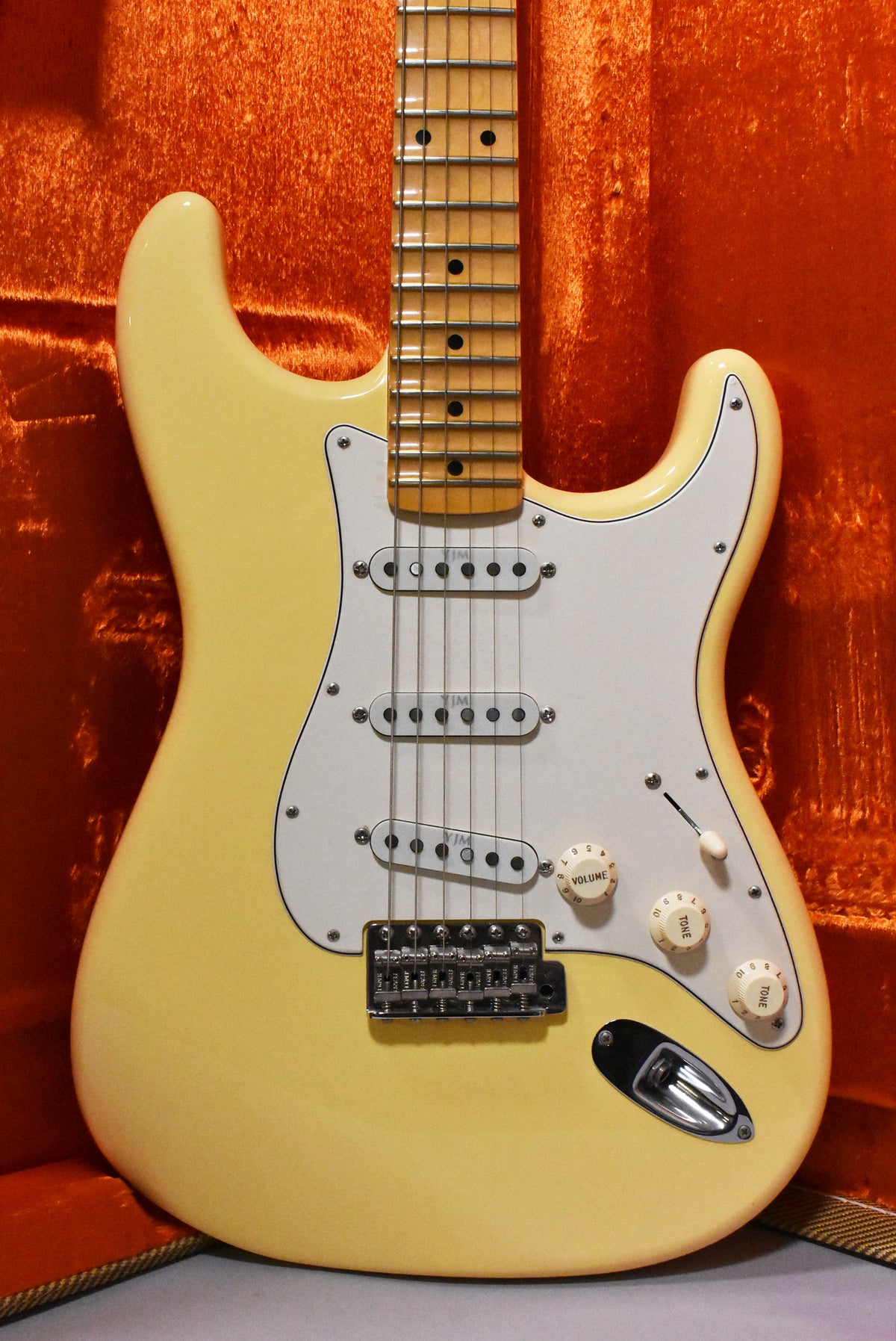Full view of a vintage white electric guitar with a maple neck, white pickguard, three single-coil pickups, and a tremolo bridge.