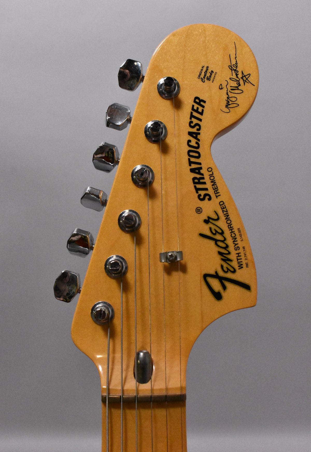 Close-up of the light maple headstock, angled slightly left, showing six chrome tuners and a string tree.