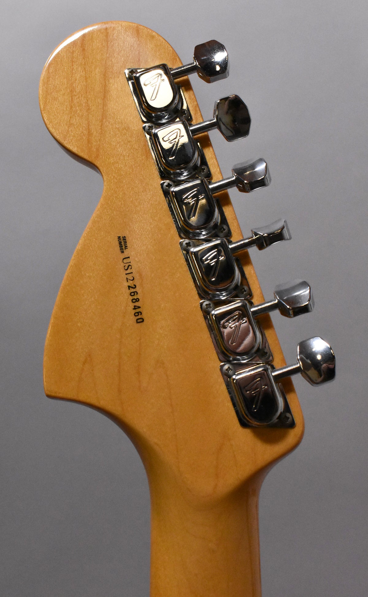 Rear view of the guitar's headstock and top of the neck, showing six chrome tuners and a glossy natural wood finish.