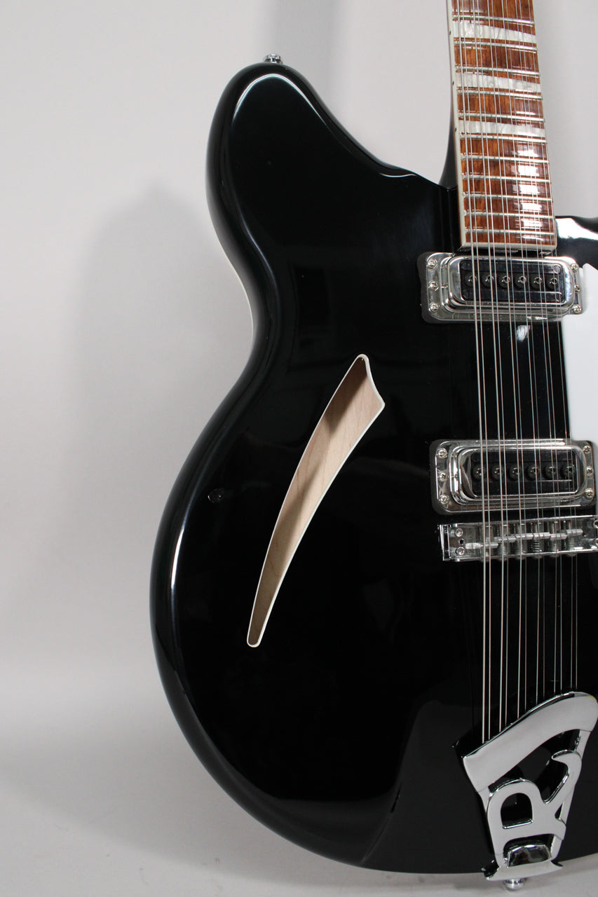 Close-up of the glossy black body, showing the f-hole, two chrome pickups, and the lower portion of the 12-string neck.