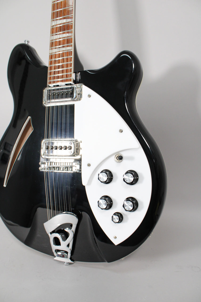 Close-up of the glossy black body, showing the white pickguard with five black knobs, two chrome pickups, and a chrome R-tailpiece.