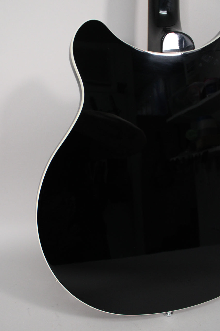 The back of the glossy black guitar body, with white binding, shows light surface scratches and a small chip on the lower bout.