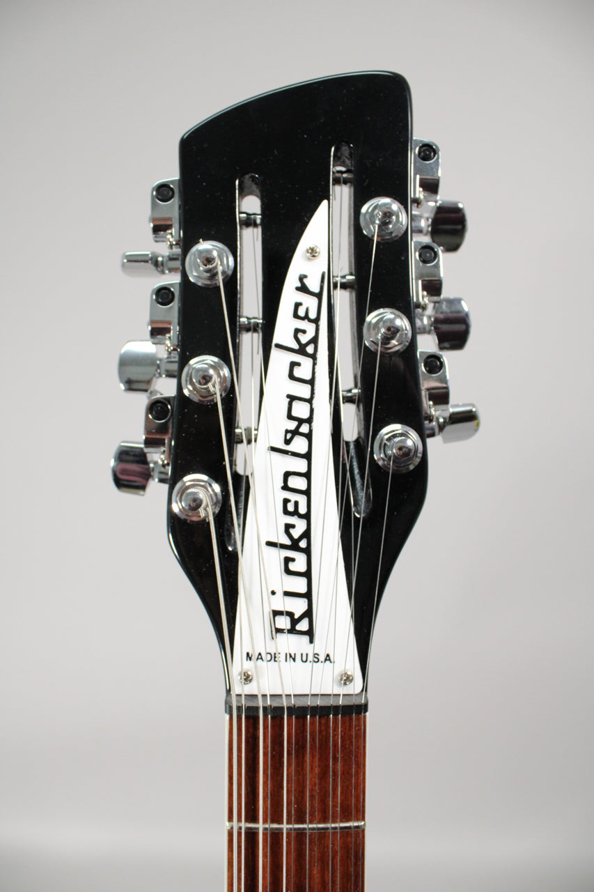 Close-up of the glossy black headstock with chrome tuners, showing the white truss rod cover and the top of the dark fretboard.
