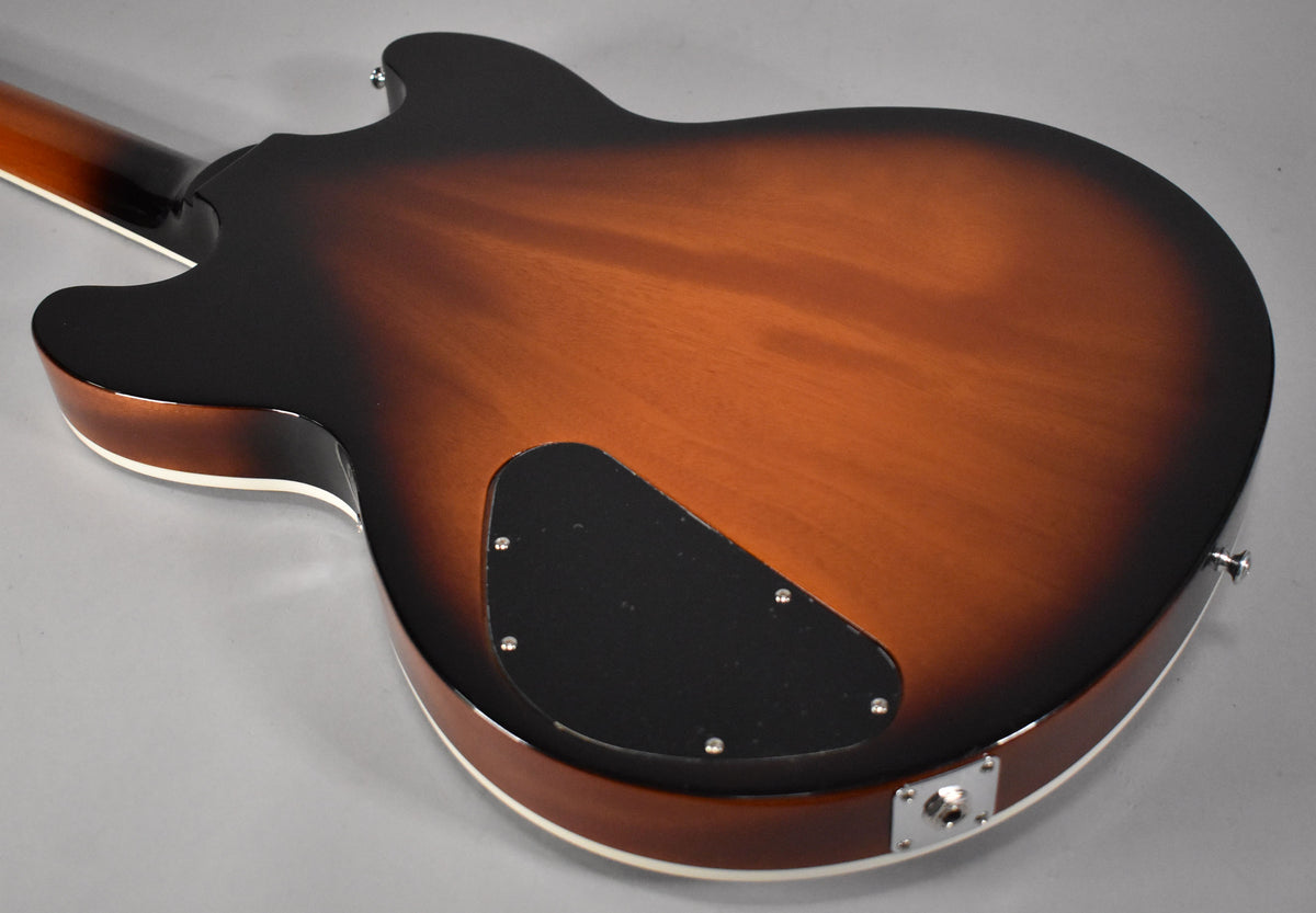 The back of a sunburst semi-hollow guitar, showing the brown center fading to dark brown edges, with a black control plate.
