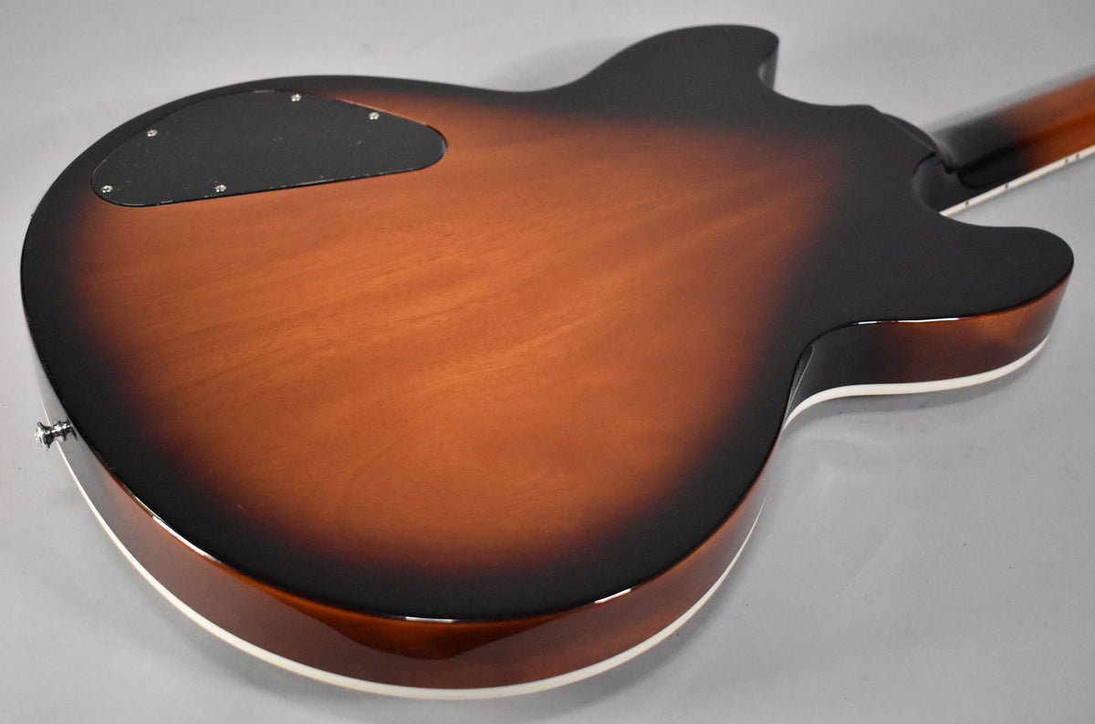 The guitar's back, in vintage sunburst, shows a black control cavity cover and white binding along the body's edge.