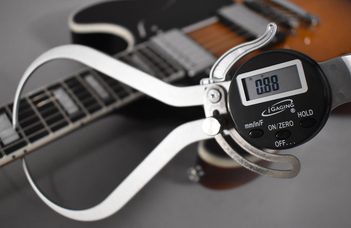A digital caliper measures the string height on the sunburst semi-hollow guitar's fretboard, showing 0.88 on its display.
