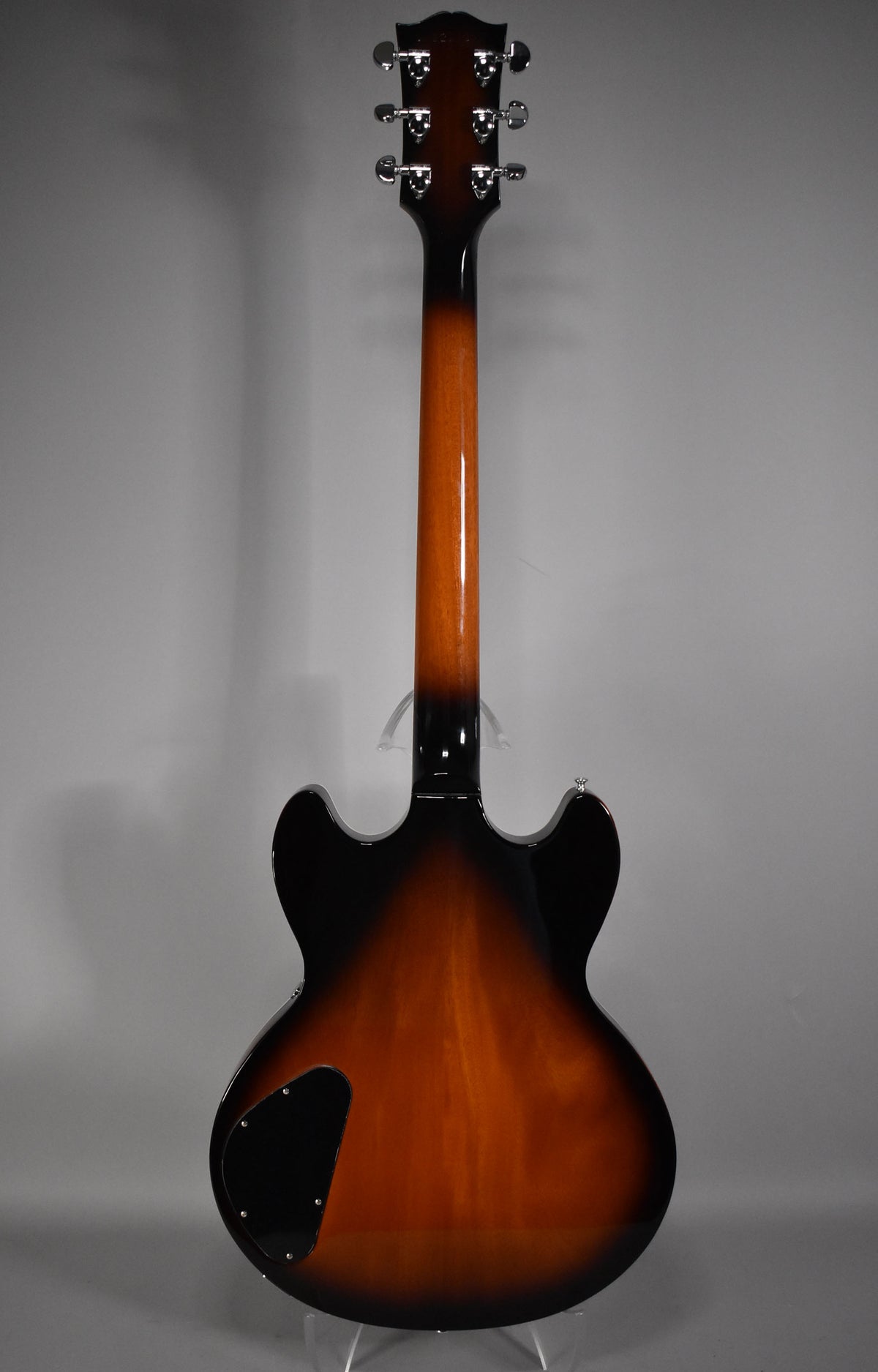 The guitar's back, headstock to body, shows a glossy sunburst finish, with a black control cavity cover on the lower bout.