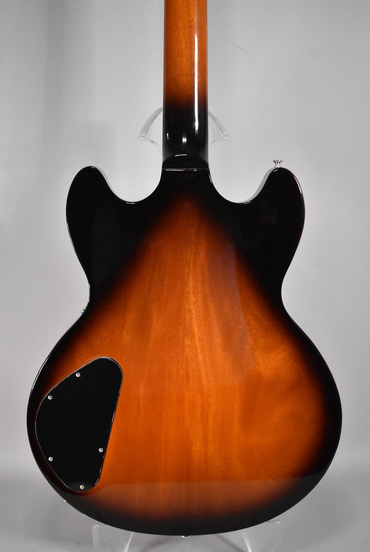 The guitar's glossy vintage sunburst back shows a black control cavity cover and a chrome strap button on the upper horn.