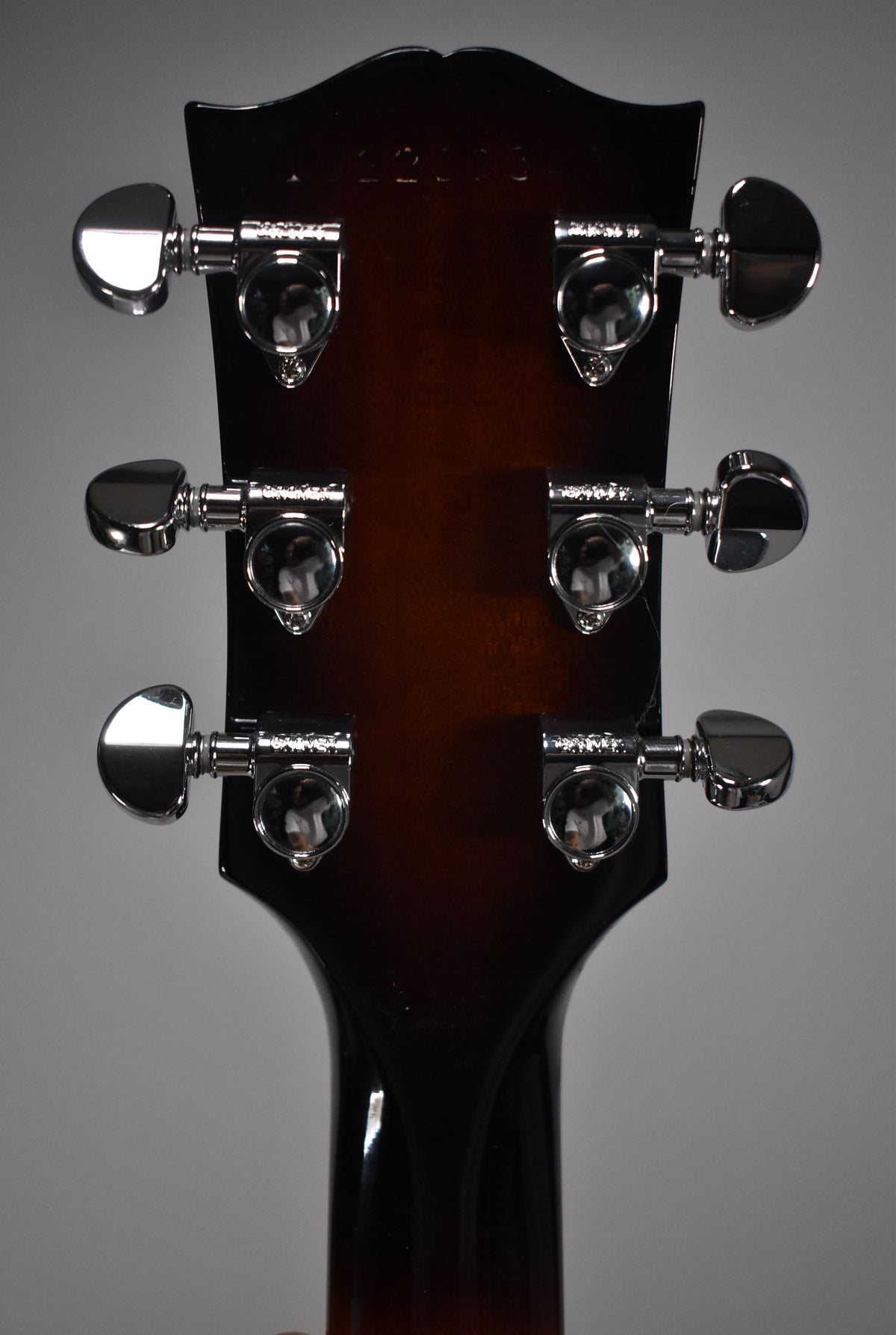 Rear view of the guitar's headstock and neck, showing six chrome tuners on a dark sunburst finish, with light wear visible.
