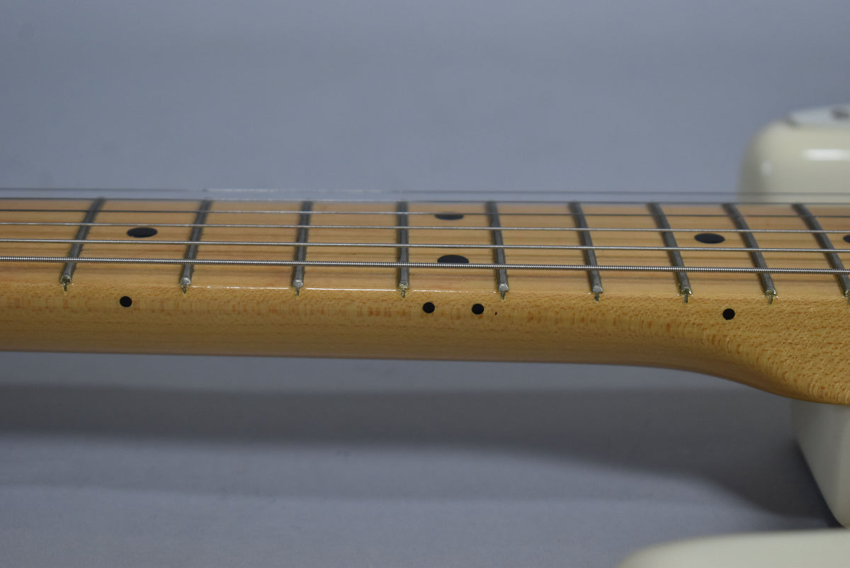 Close-up of the light maple neck and fretboard, showing dark dot inlays and light fret wear on the lower frets.