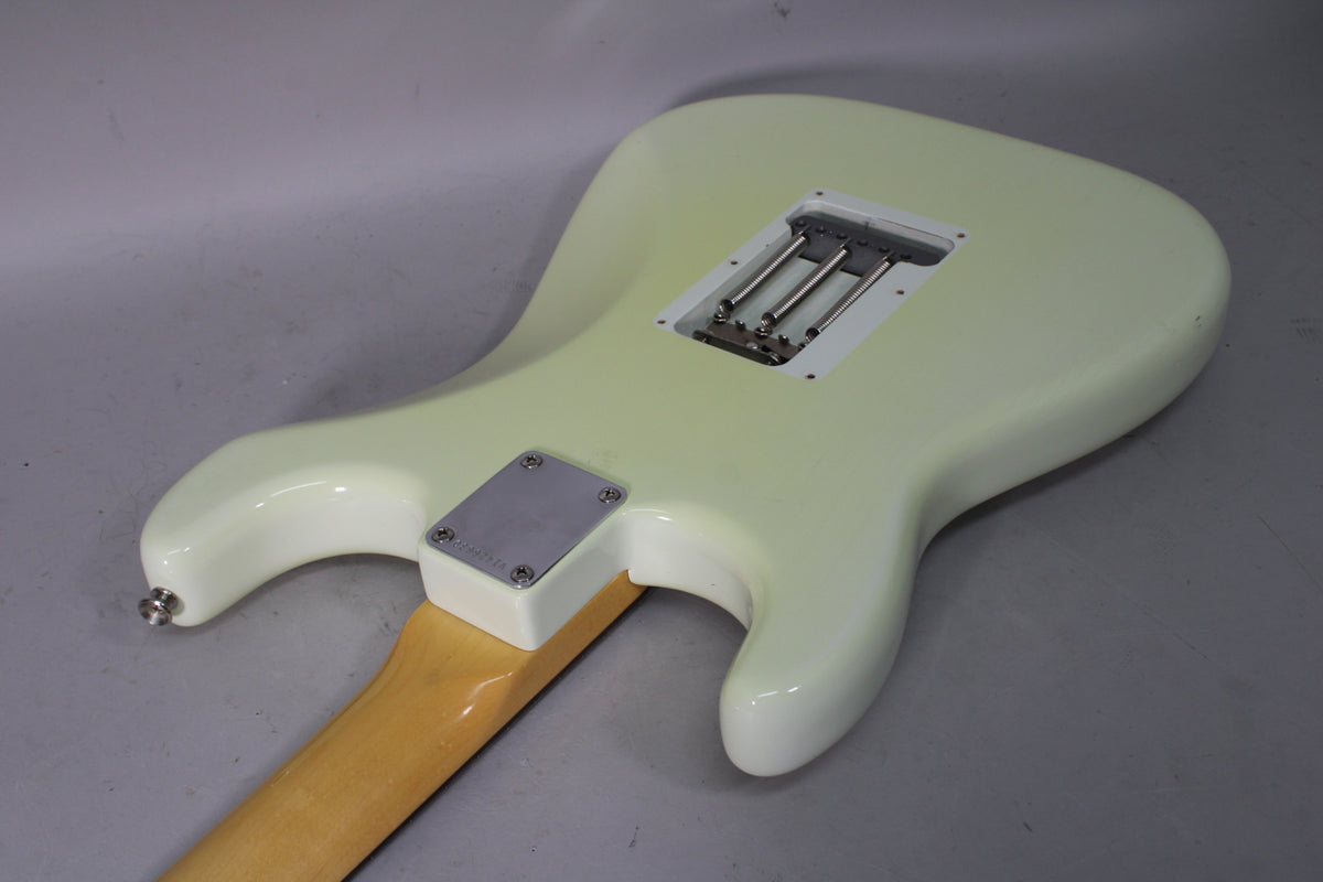 The back of an Olympic White guitar shows a tremolo spring cavity, neck plate, and a small chip on the upper bout.
