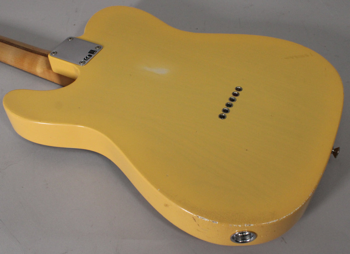 The blonde Telecaster's back shows a worn finish with visible checking, a neck plate, six string ferrules, and an output jack.
