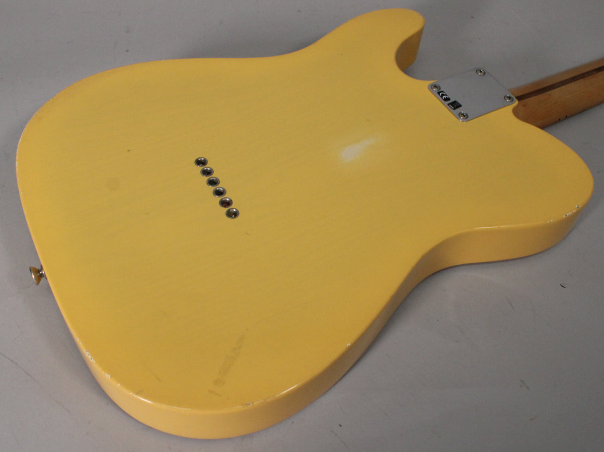 The back of a blonde Telecaster body, angled from the lower left, shows string-through ferrules, a neck plate, and light wear.