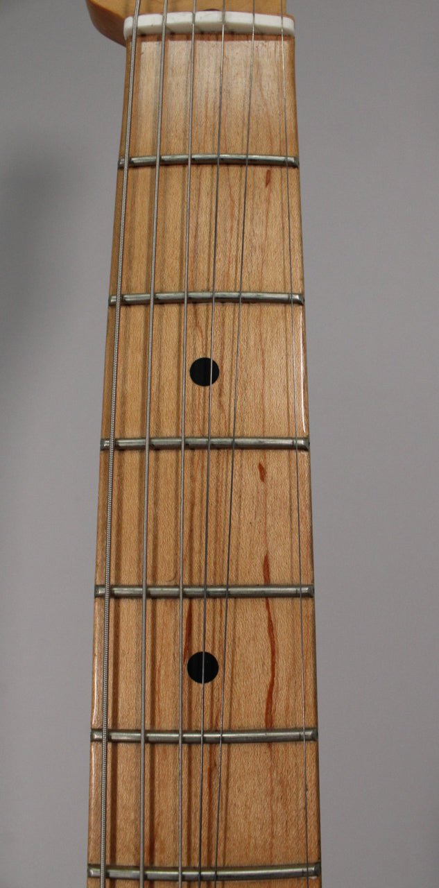 Close-up of the maple fretboard with black dot inlays, showing light wood grain and a white nut at the top.