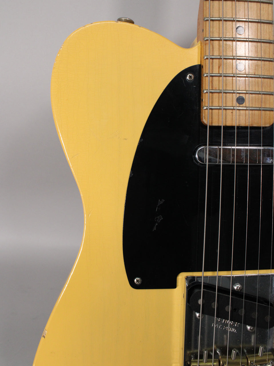 Close-up of the blonde Telecaster's upper body, showing a black pickguard, maple fretboard, and visible finish checking and wear.