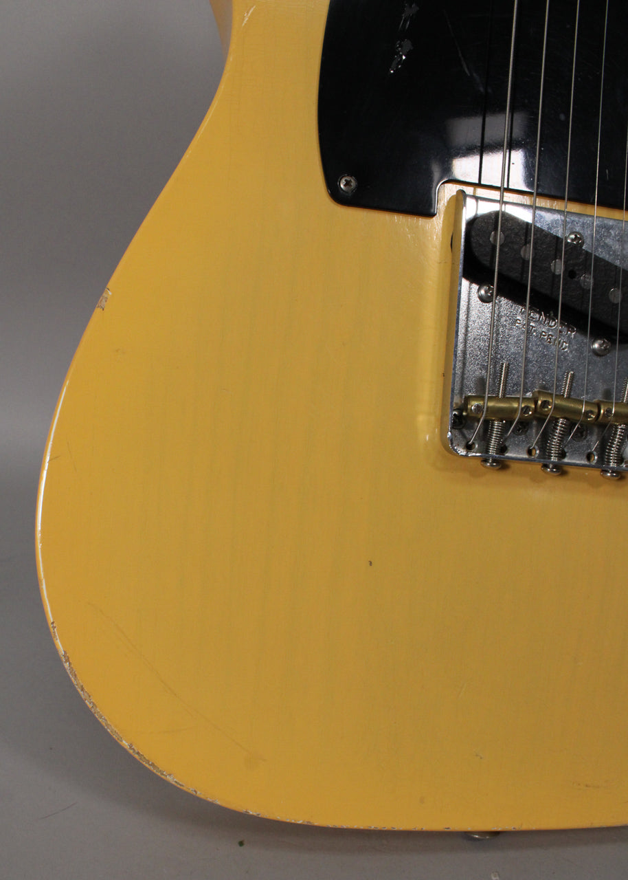 Close-up of the blonde body, showing a black pickguard, chrome bridge with brass saddles, and heavy wear on the lower bout.