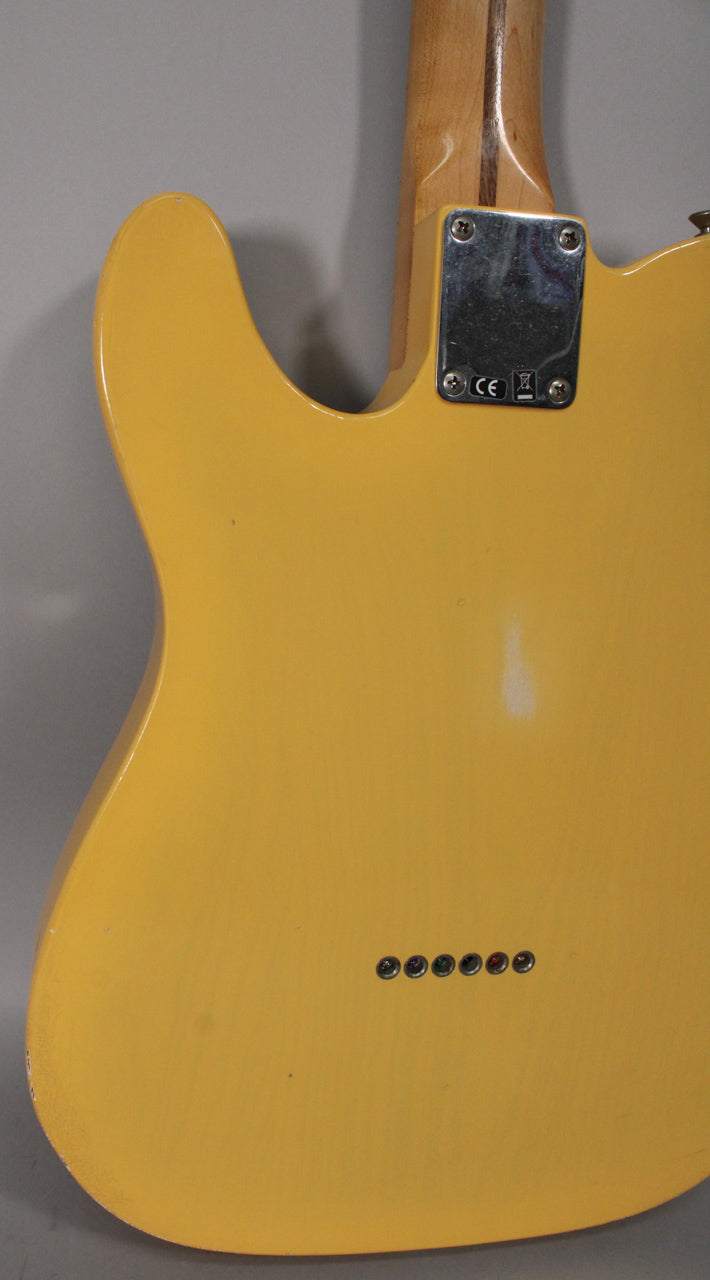 The back of a blonde Telecaster body with a worn finish, showing the neck plate, string-through ferrules, and some edge wear.