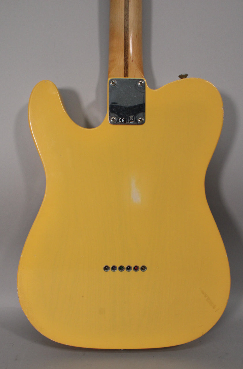 The back of a blonde Telecaster body with a maple neck, showing a chrome neck plate, six string ferrules, and light wear.