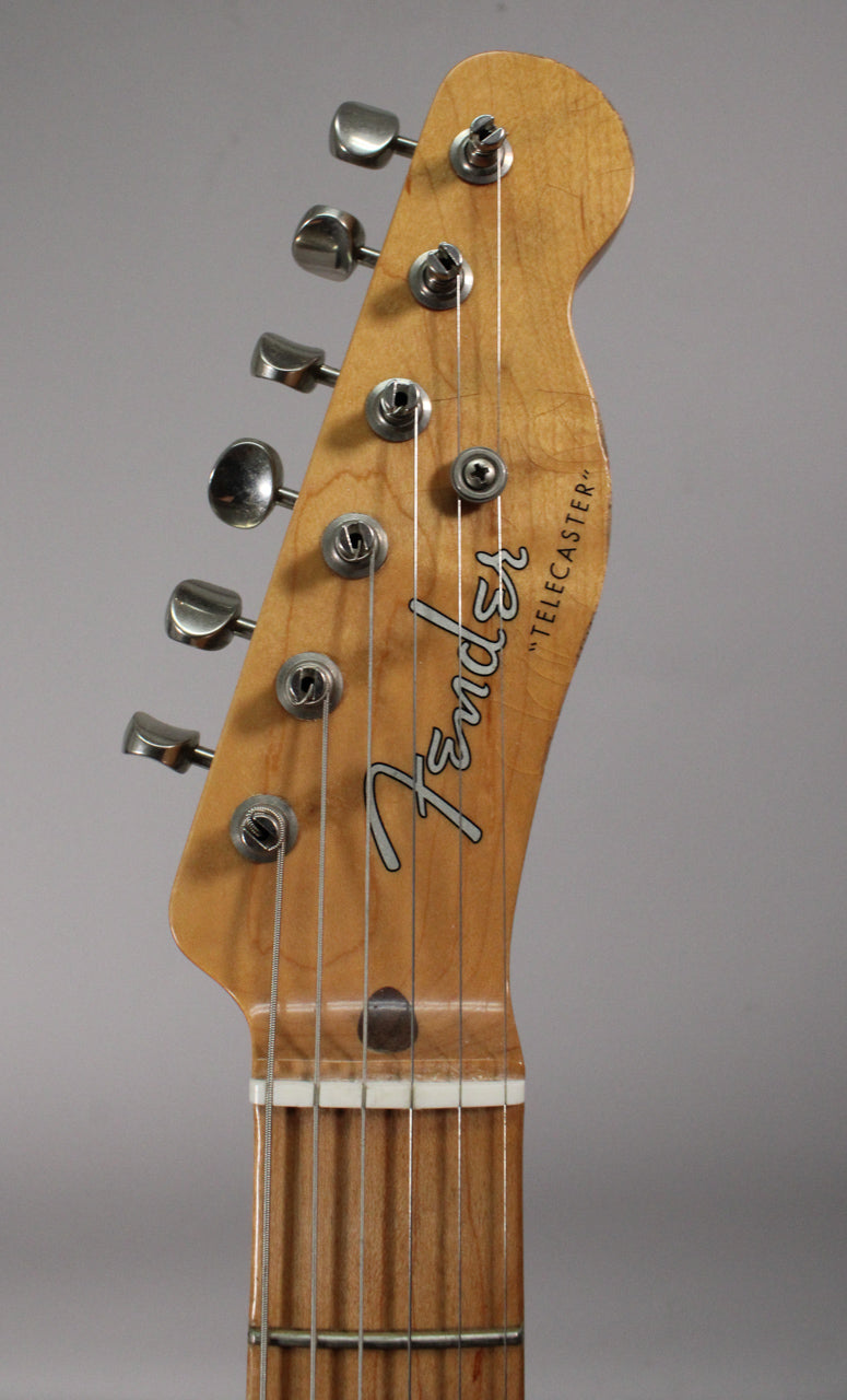 Close-up of the light blonde headstock with six chrome tuners, showing finish checking and wear around the edges.