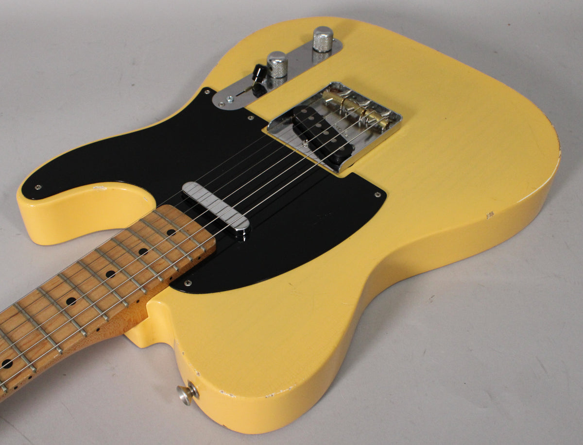 Blonde Telecaster body with black pickguard, maple neck, chrome hardware, and visible wear on the body edges and neck.